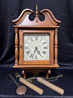 Front view of clock showing case, dial, weights, pendulum