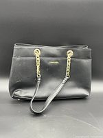 Front view of black Calvin Klein shoulder bag showing gold-tone chain handles and logo