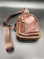 Front view showing leather bag, strap, zippers, logo