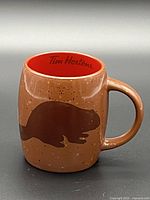 Side view showing beaver silhouette graphic on brown speckled mug