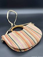 Front of woven striped half-moon handbag showing bamboo-look handle and strap