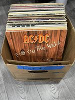 Box of vinyl LPs with AC/DC “Fly on the Wall” at front