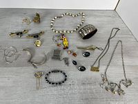 All items laid out showing variety of costume jewellery, pins, keychains, bracelets and necklaces