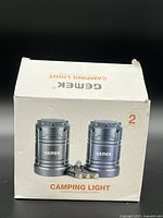 Front of box showing two Gemek camping lights and batteries