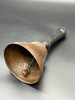 Angled view showing bell mouth, interior clapper, wooden handle