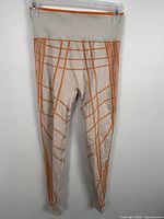Front view of beige leggings with orange stripe pattern