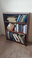 Front view of wooden 3-shelf bookcase with books (books not included)