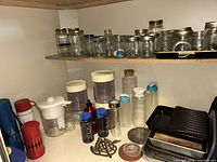 Shelf with mason jars, pitchers, water bottles, bake pans