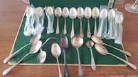 All spoons and ladle laid out on green felt