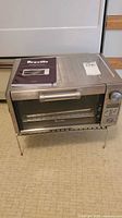 Front view of Breville BOV450XL oven with manual on top