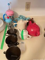 Group shot showing French press, several teapots, three brown mugs