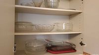Cabinet shelves holding mixing bowls, scalloped bowl, casserole and rectangular dishes