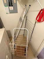 ironing board, drying rack, and wheeled wire cart grouped together