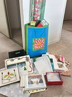 Assorted holiday wrap rolls in blue floral gift bag, boxed cards, loose cards, tissue paper