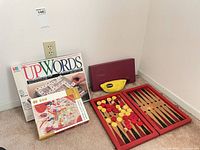 Group shot of all items: Upwords box, puzzle box, Bananagrams pouch, folded open Backgammon board with pieces