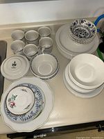Full view of approximately 28 mixed dinnerware items on countertop