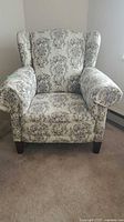 Front view of floral tapestry wingback armchair
