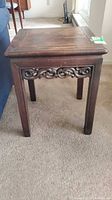 Front view of carved solid wood side table showing apron detail and legs