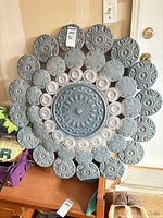 Front view of round metal wall medallion against wall showing full design