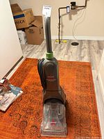 Full view of the Bissell carpet cleaner standing on a rug showing entire unit and cord