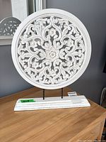 Front view of white carved round plaque on stand