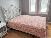 full view of assembled bed with ornate cream metal headboard and bedding