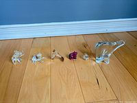 Group shot of all four glass animal figurines lined up on wood floor