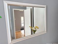 Front view of white framed mirror on grey wall