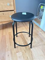 Full view of black metal stool showing seat and legs