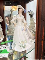 Front view of Royal Doulton “ADELÉ” figurine in cabinet
