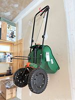Full view of green Scotts EdgeGuard broadcast spreader hanging on wall