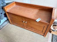 Front view of wooden storage bench showing two doors and surface wear