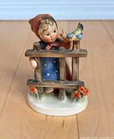 Front view of Goebel Hummel figurine showing child, fence, bird and base details