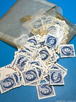 Pile of blue Canadian 5¢ Queen Elizabeth II stamps spilling from glassine envelope
