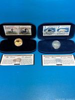 Both open presentation cases showing coins, stamps, COAs