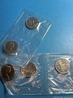 Five sealed coins in two segments of original plastic strip