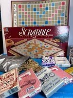 Scrabble box, board, tiles, racks and multiple card decks displayed