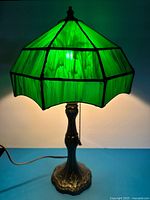 Lamp lit showing full green stained glass shade and metal base