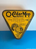 Top view of yellow triangular tin showing main O-Cedar Mop Polish graphics
