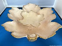 Top view of nested beige ceramic leaf bowls showing gold rims and vein texture