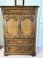 Front view showing entire armoire with carved doors, drawers, and hardware