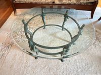 Full view of assembled round glass coffee table showing glass top and verdigris metal base