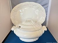 Tureen with lid and ladle in front of platter