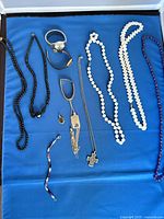 Necklaces, bracelets, wristwatch and pendants on blue cloth