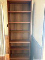 Full front view of tall wood bookcase showing six shelves