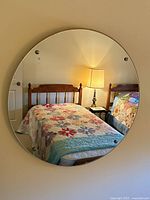 Front view of round mirror on wall reflecting bedroom
