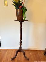 Full view of wood pedestal stand with pot and artificial plant