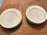Two stacks of white dinner plates with gold rim