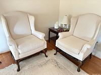 Front view of both armchairs showing upholstery and wooden legs