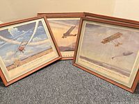 Three of the framed aviation prints displayed on carpet showing artwork and frames